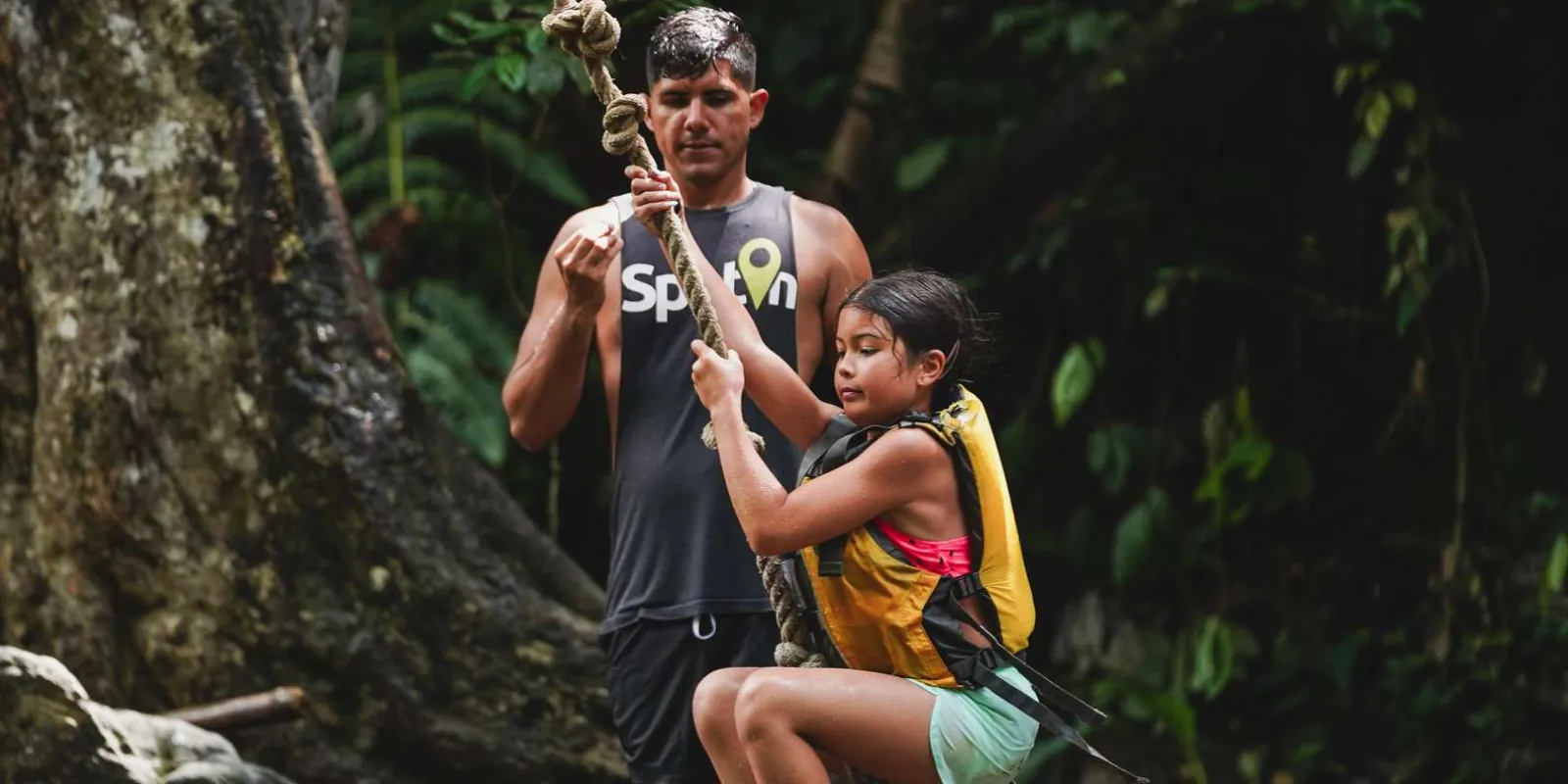 A guide steadying a young guest on the rope before her turn on the swing
