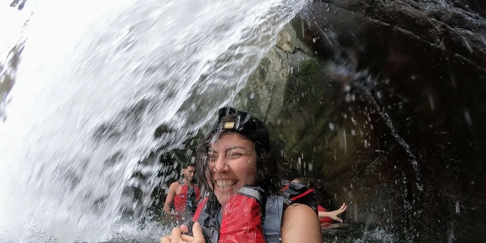 A guest laughing under the falling water at the rainforest pool