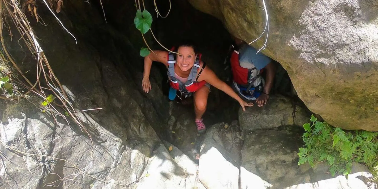 Guests in life vests climbing up through a narrow rock gap