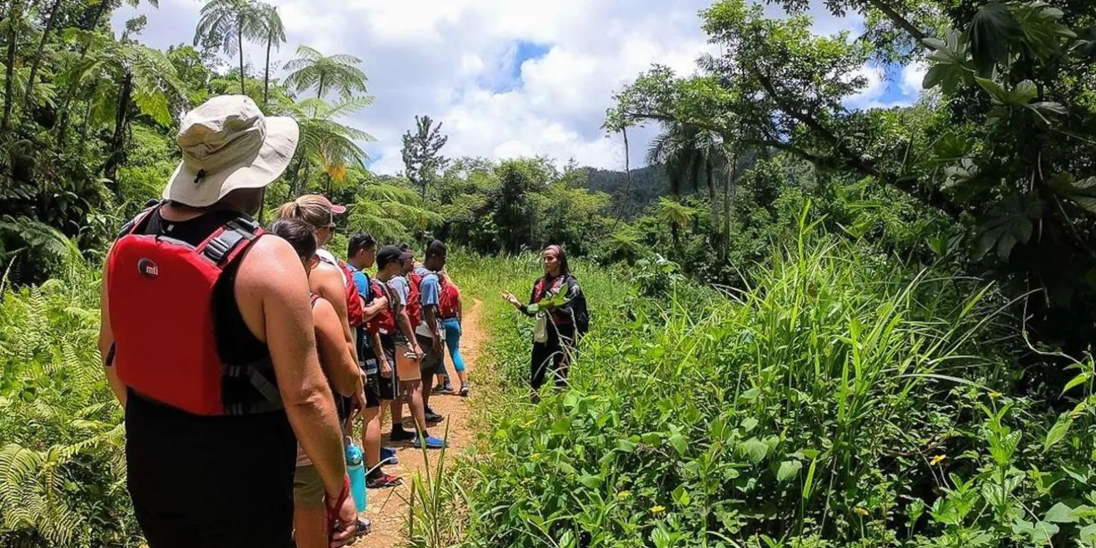 The group walking the trail in red life vests on the way to the water