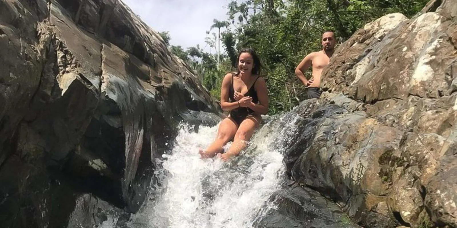 Two guests sitting in the current where the water spills over the rock