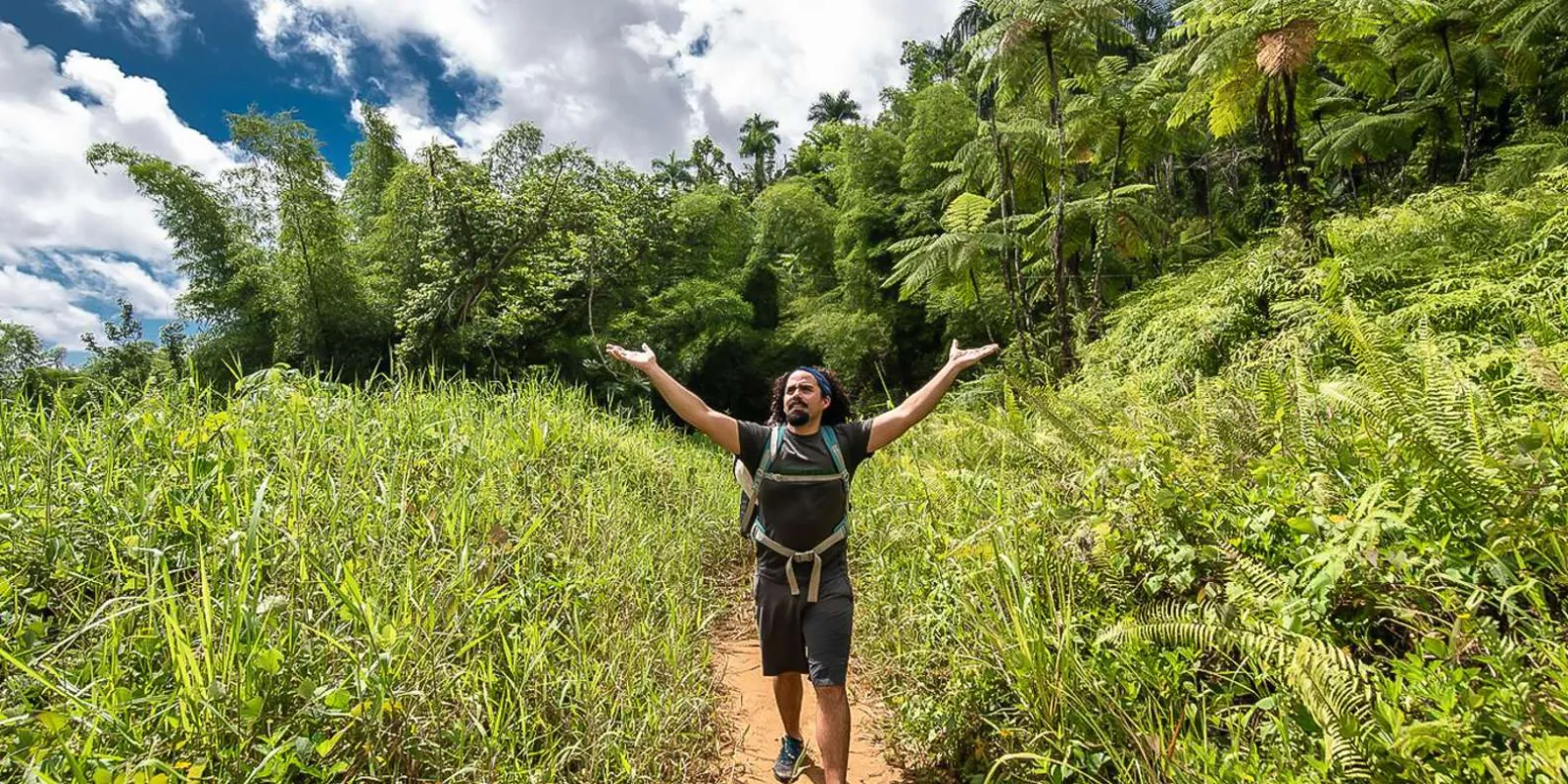 A hiker with arms outstretched on the open trail above the treeline