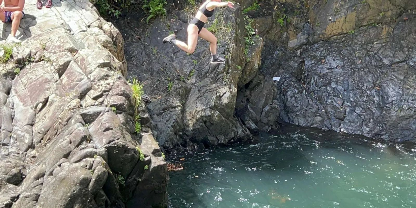 A guest jumping from the rock ledge into the pool below